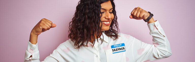 A woman wearing a nametag that says "Hello I am Dreamer" and flexing her muscles.