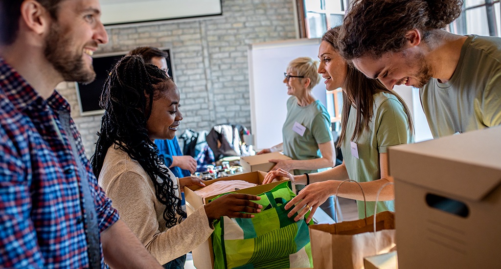 A group of people work together to pack reusable bags and cardboard boxes on a table.