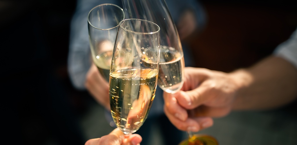 Three people clinking champaign flutes together.